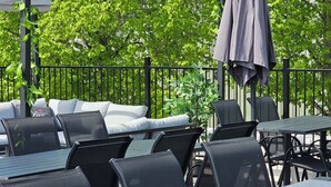 An outdoor seating area with tables and chairs, a pergola with string lights, and a covered umbrella. - Teatterihotelli Riihimäki (Riihimaki)