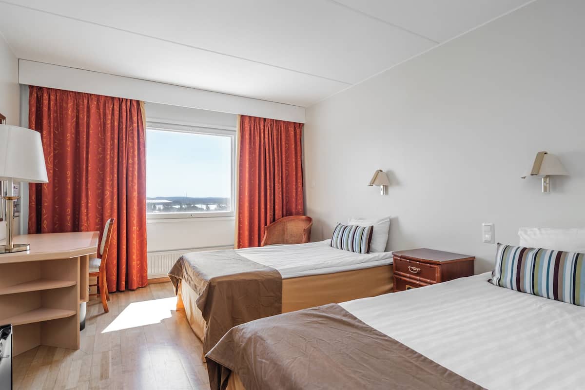 Ein Hotelzimmer mit zwei Betten, einem Schreibtisch und einem Stuhl.