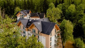 A multi-story building with a modern architectural design, featuring balconies and large windows. - Green Apartments (Karpacz)
