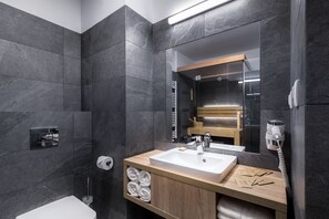 A modern bathroom with dark tiles, a wooden vanity, a white sink, and a towel rack. - Green Apartments (Karpacz)