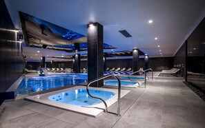 A modern indoor pool area with multiple hot tubs and lounge chairs, featuring a sleek design and ample seating. - Green Apartments (Karpacz)