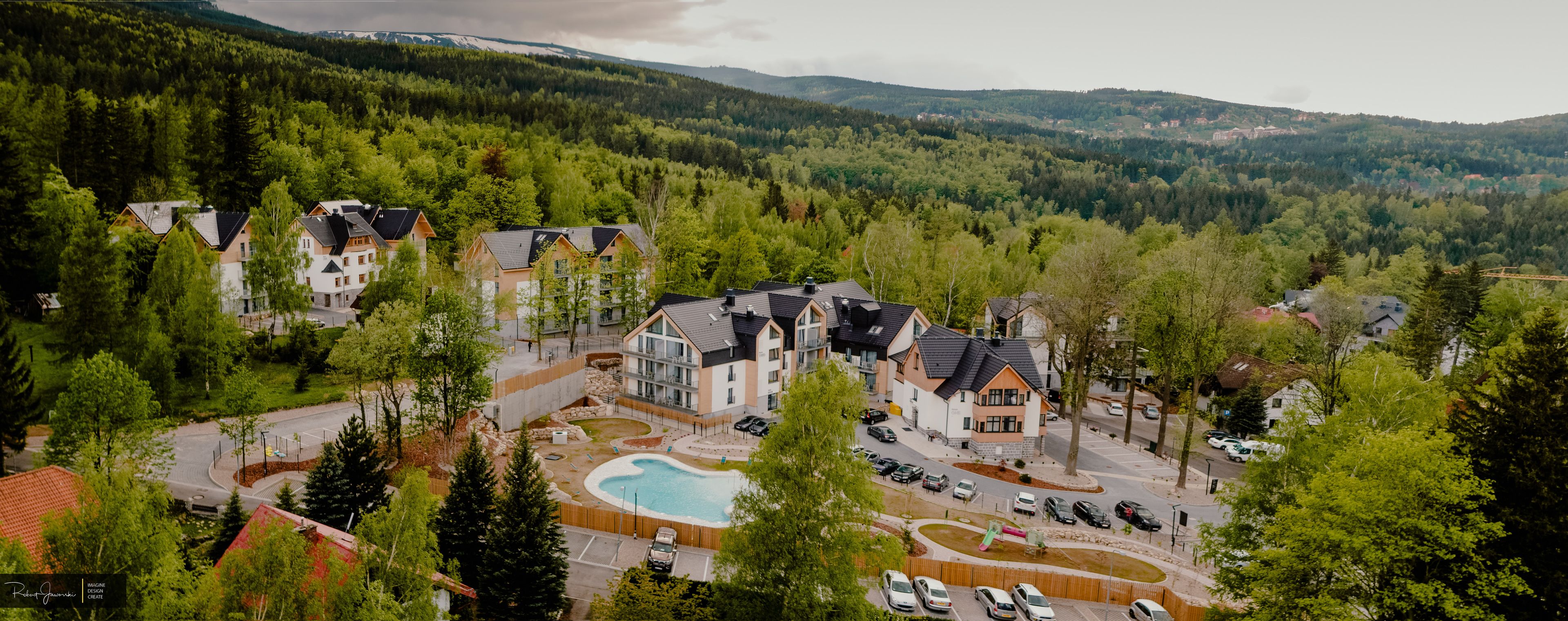 A residential area with multiple houses, a swimming pool, and a parking lot.