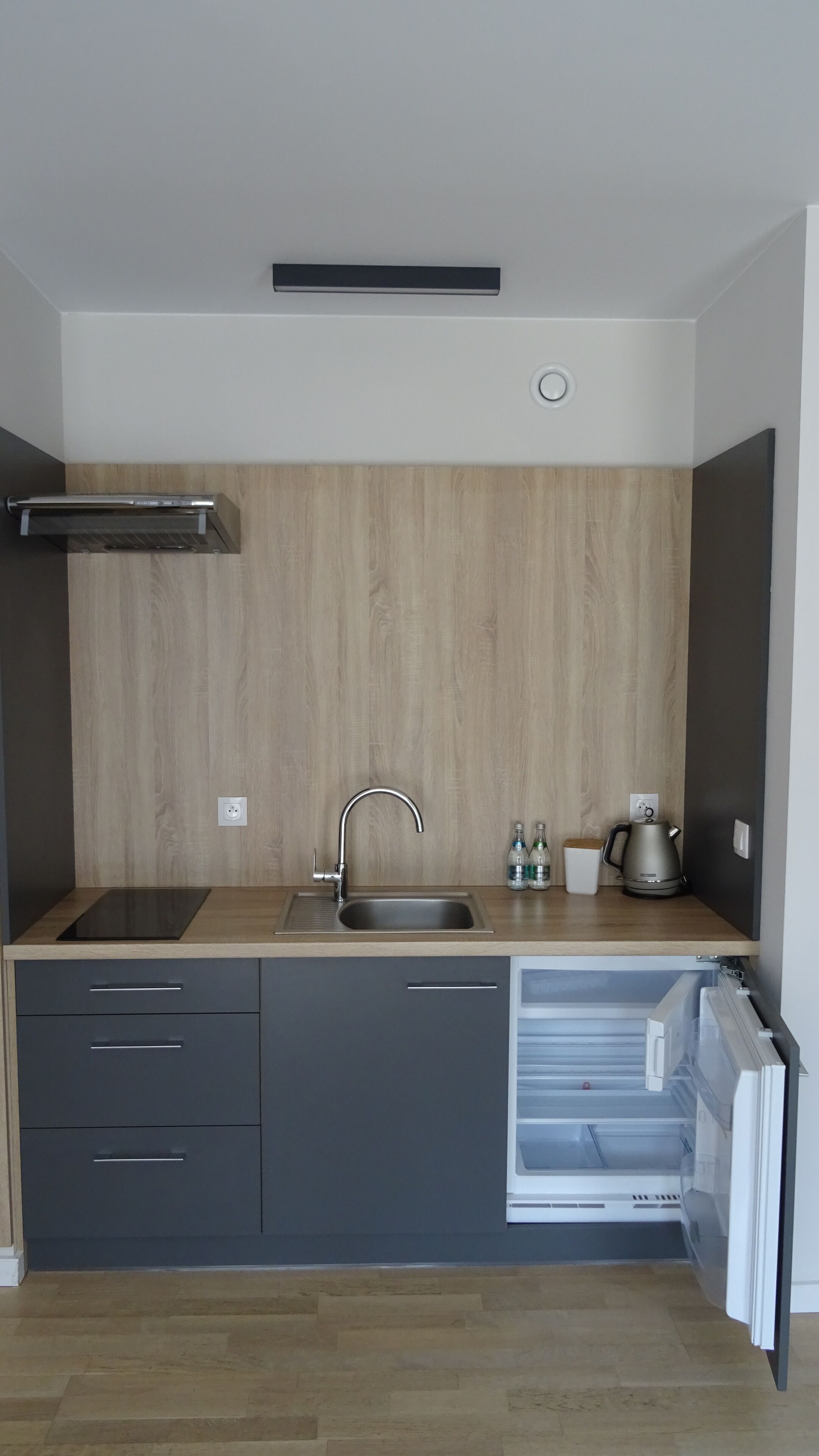A modern kitchen with a wooden backsplash, a built-in sink, a stove, and a dishwasher.
