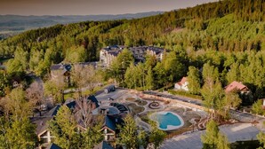 An aerial view of a resort with a large building, multiple smaller structures, and a swimming pool. - Green Apartments (Karpacz)