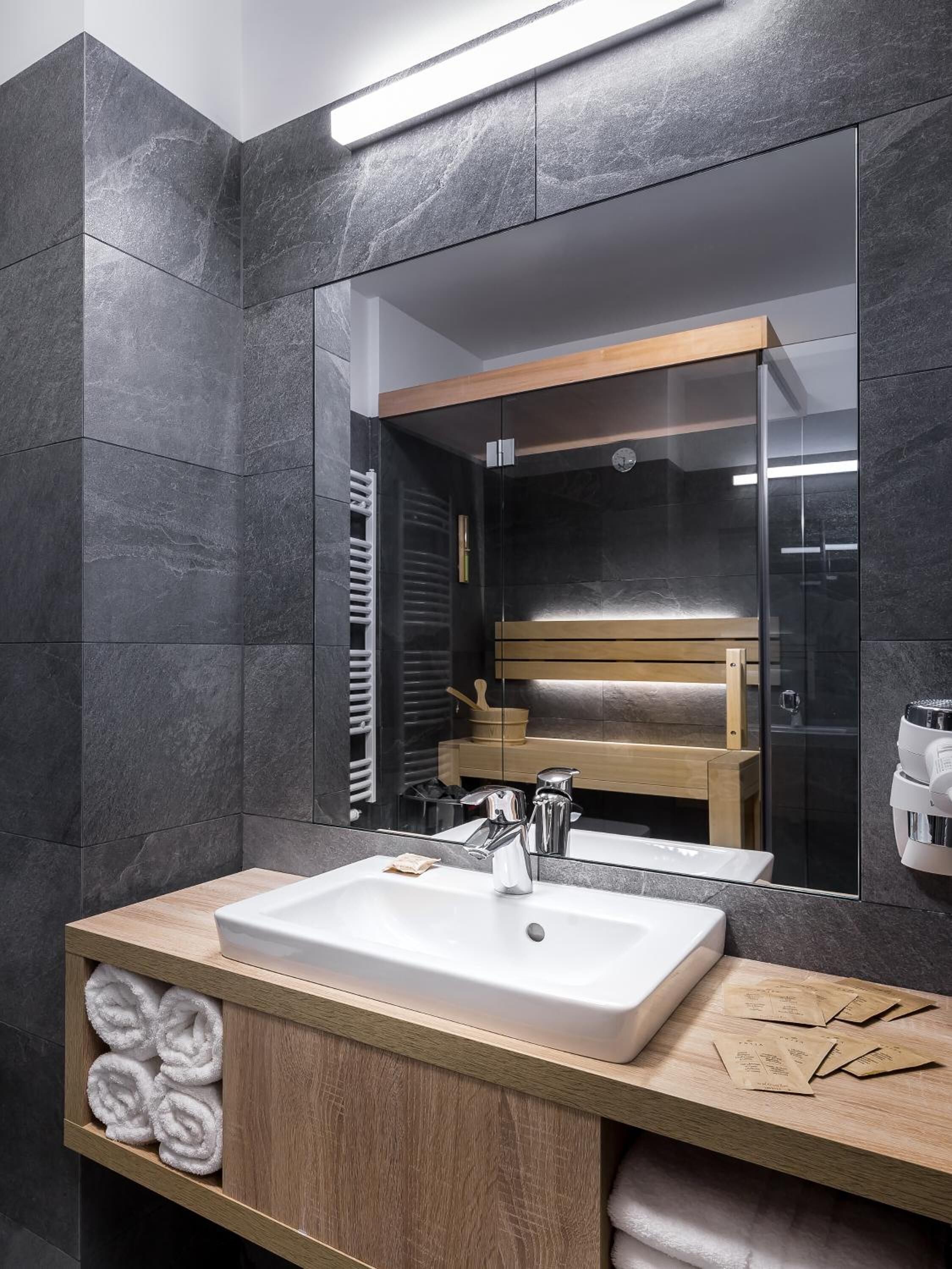 Un baño moderno con un espejo grande, un lavabo blanco y un mueble de tocador de madera.