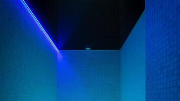 Un baño moderno con una bañera grande, iluminación LED azul y un perchero para toallas.