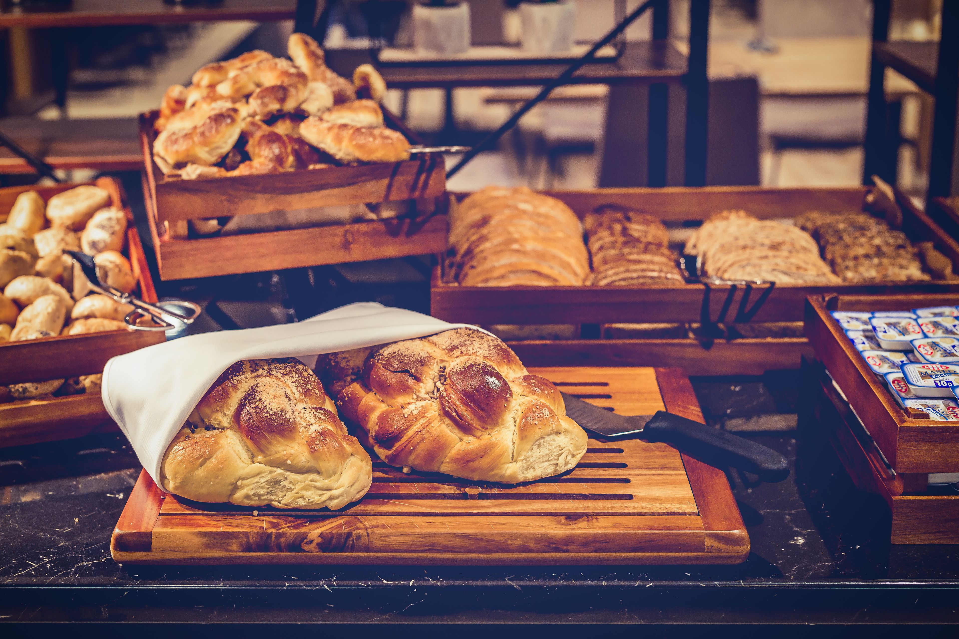 Une variété de pains et de viennoiseries présentés sur des étagères en bois dans une boulangerie.