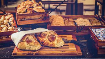 Une variété de pains et de viennoiseries présentés sur des étagères en bois dans une boulangerie.