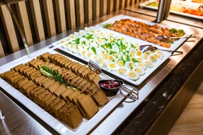 A buffet with various food items including sliced bread, eggs, and meat. - Green Apartments (Karpacz)