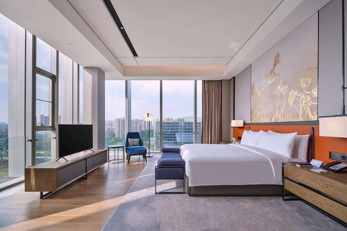 Une chambre d’hôtel moderne équipée d’un grand lit, d’un bureau, d’une chaise et d’un téléviseur.