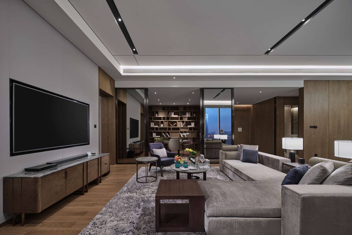 Un salon moderne avec un grand téléviseur à écran plat, un canapé, une table basse et une bibliothèque.