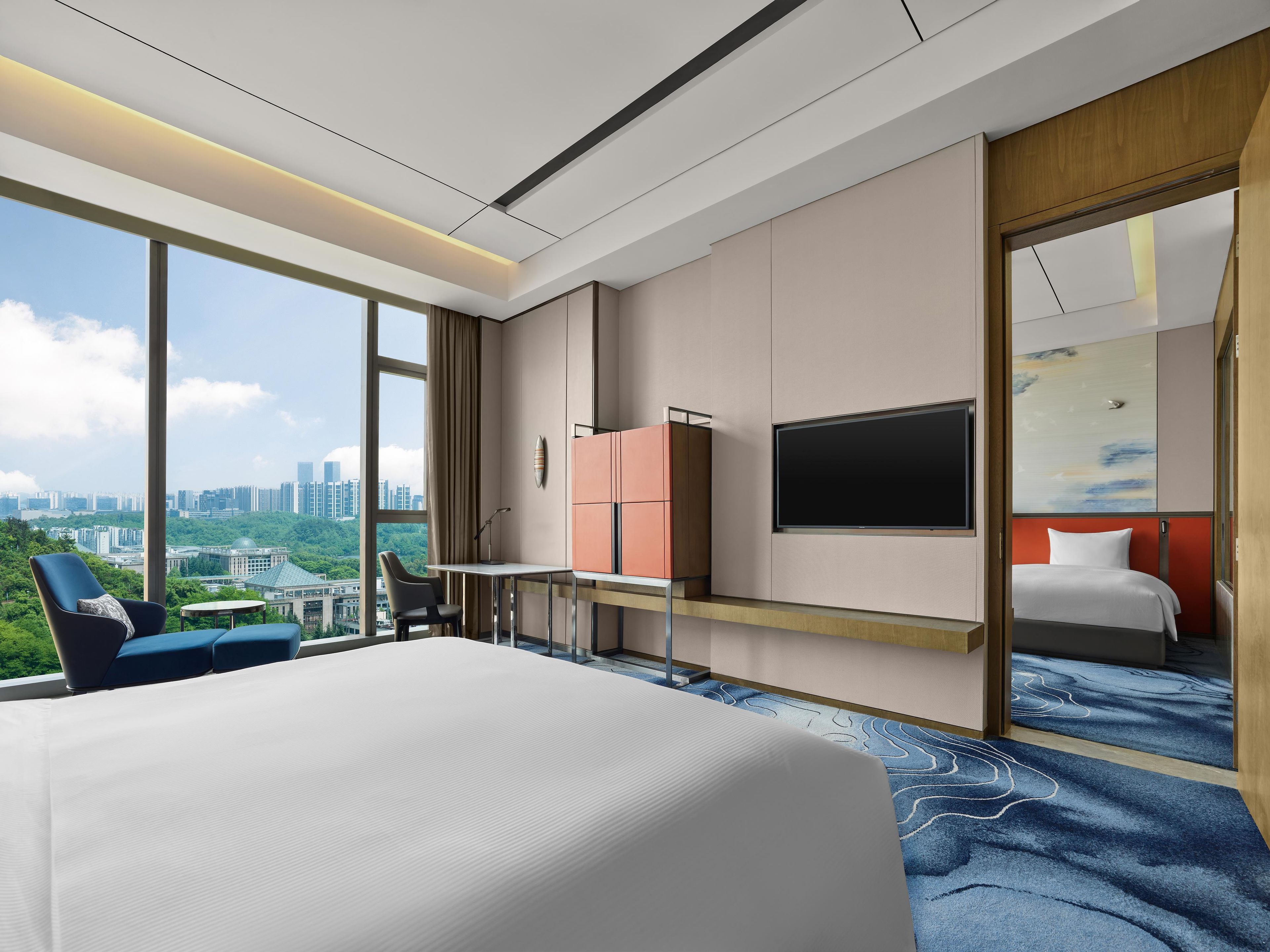 A hotel room with a large bed, a desk, a chair, and a TV.