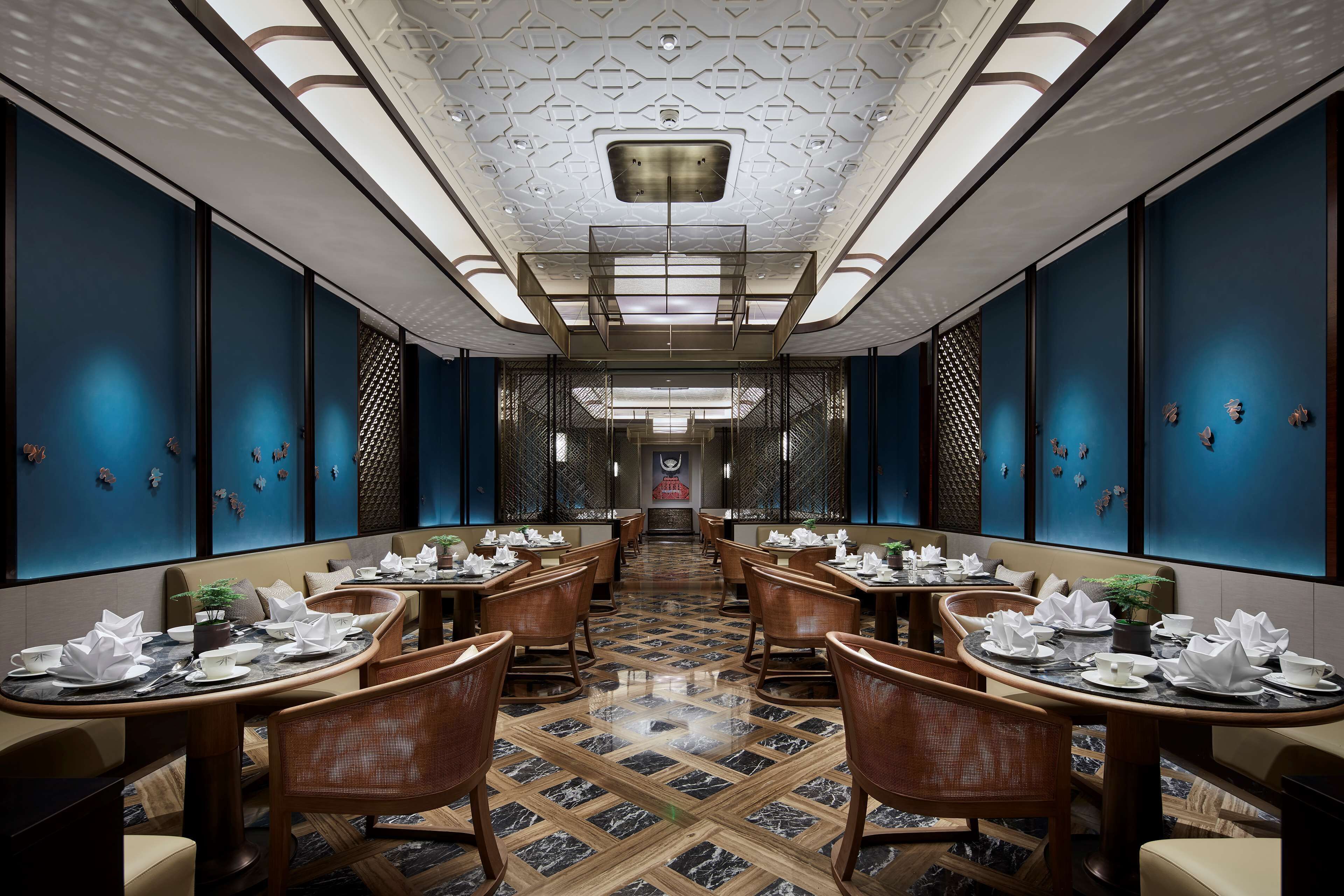 Un restaurant avec une grande table centrale, des murs bleu foncé et un sol à motifs.