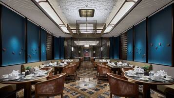 Un restaurant avec une grande table centrale, des murs bleu foncé et un sol à motifs.