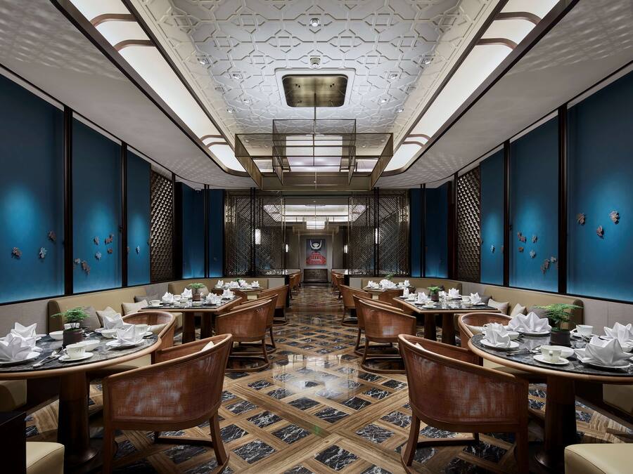 Un restaurant avec une grande table centrale, des murs bleu foncé et un sol à motifs.