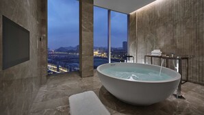 Um banheiro moderno com uma banheira grande, vista para a cidade e um espelho amplo.