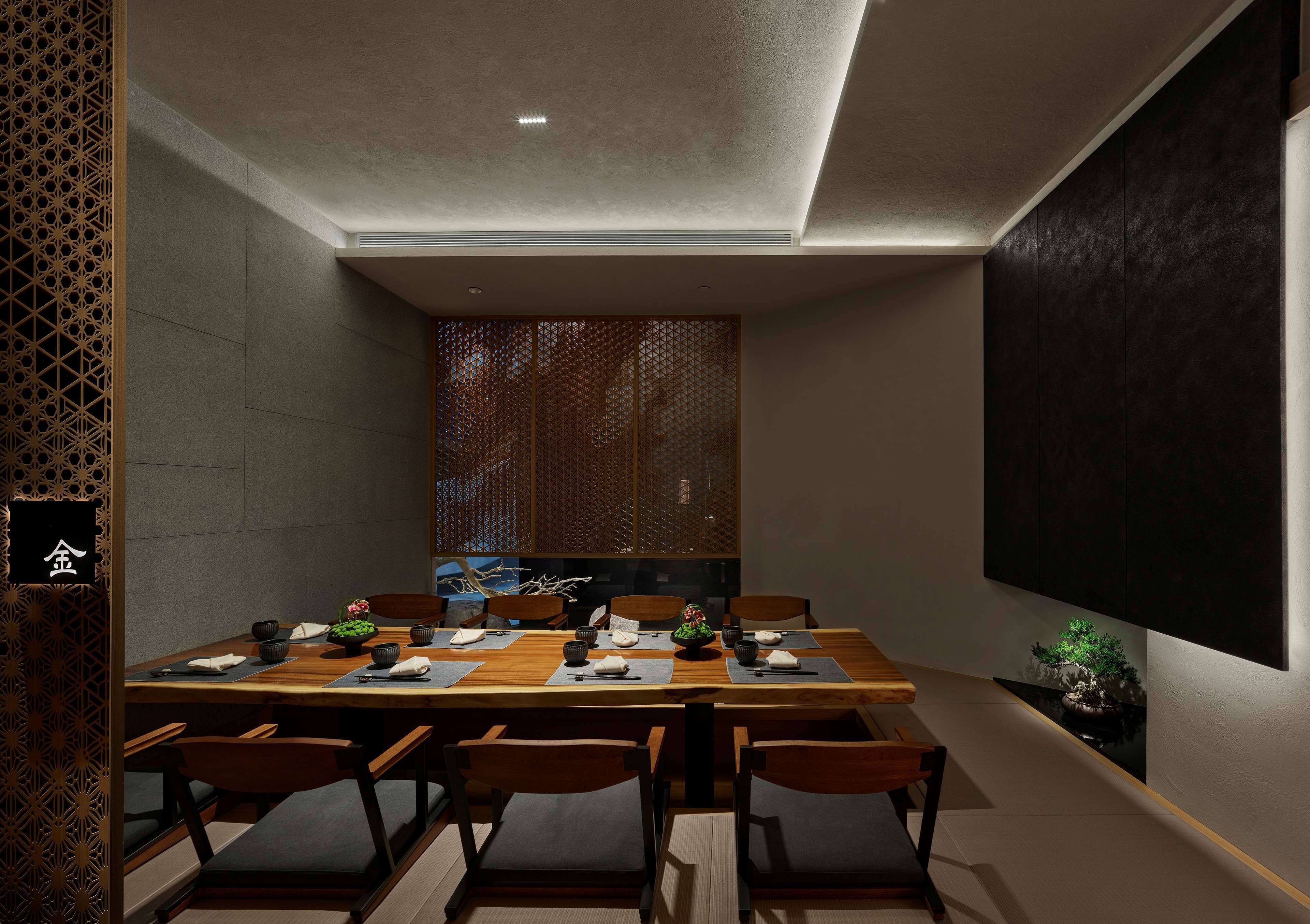 A modern dining room with a long wooden table, six chairs, and a decorative screen in the background.