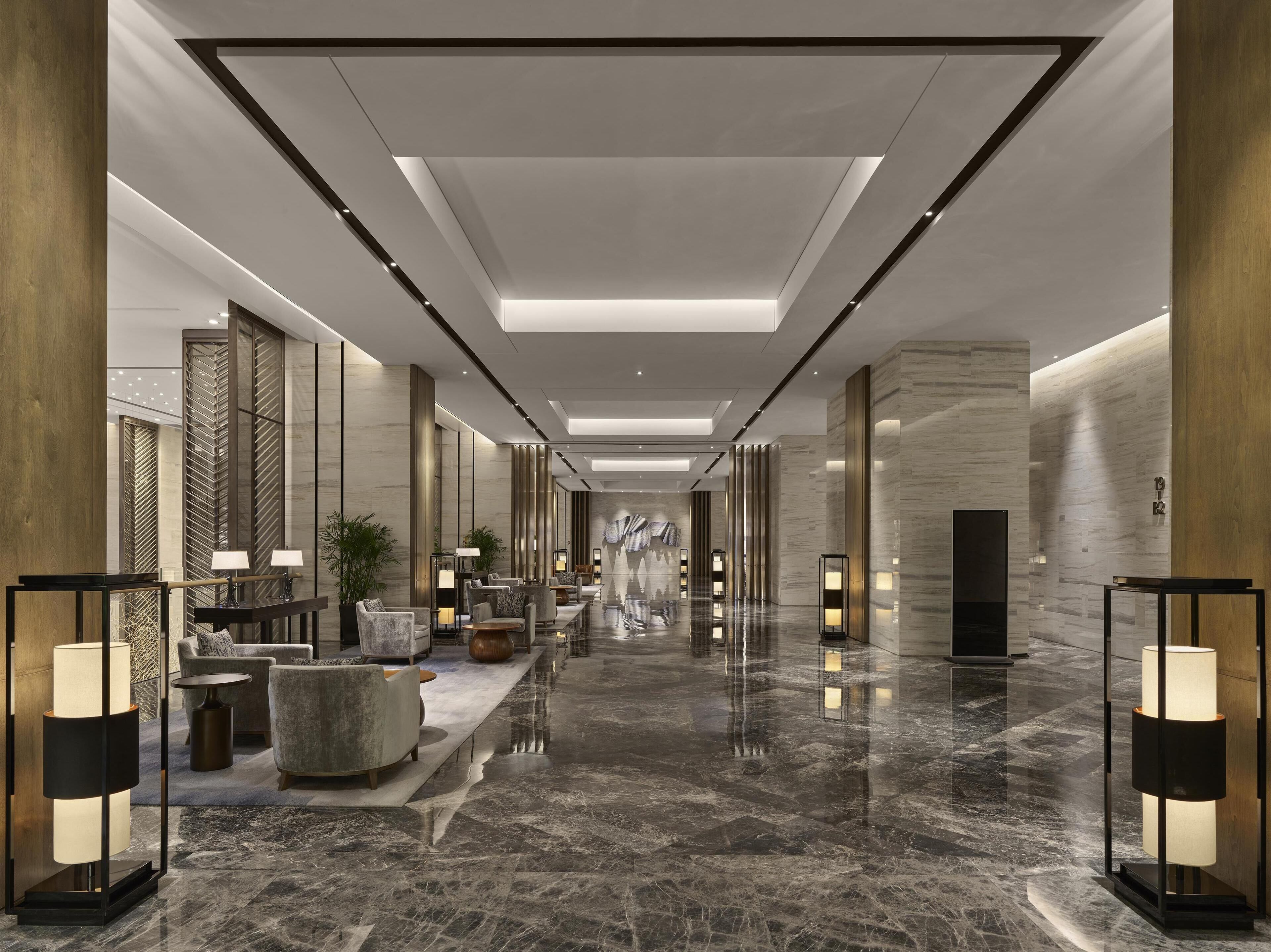 A modern lobby with a marble floor, seating areas, and ambient lighting.