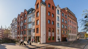 A multi-story residential building with a mix of brick and modern facade, featuring balconies and large windows.