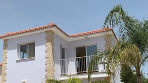 Ein zweistöckiges Gebäude mit weißer Fassade, beigen Backstein-Akzenten und einem roten Ziegeldach.