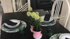 Ein Esstisch ist gedeckt mit Tellern, Servietten und einer Blumenvase.
