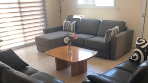 Ein Wohnzimmer mit grauem Sofa, einer schwarzen Ledercouch und einem Holztisch.