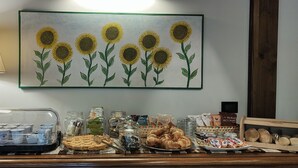 Un buffet de petit-déjeuner proposant une variété d’aliments, et une peinture de tournesols accrochée au mur.