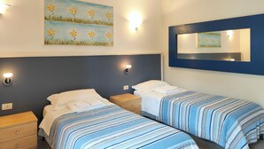 Une chambre d’hôtel avec deux lits, un tableau au mur et un miroir.