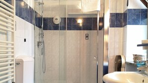 Une salle de bain moderne avec une douche à parois de verre, deux toilettes, un lavabo et un porte-serviettes.