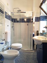 Un bagno moderno con doccia vetrata, due servizi igienici, un lavandino e un porta asciugamani.