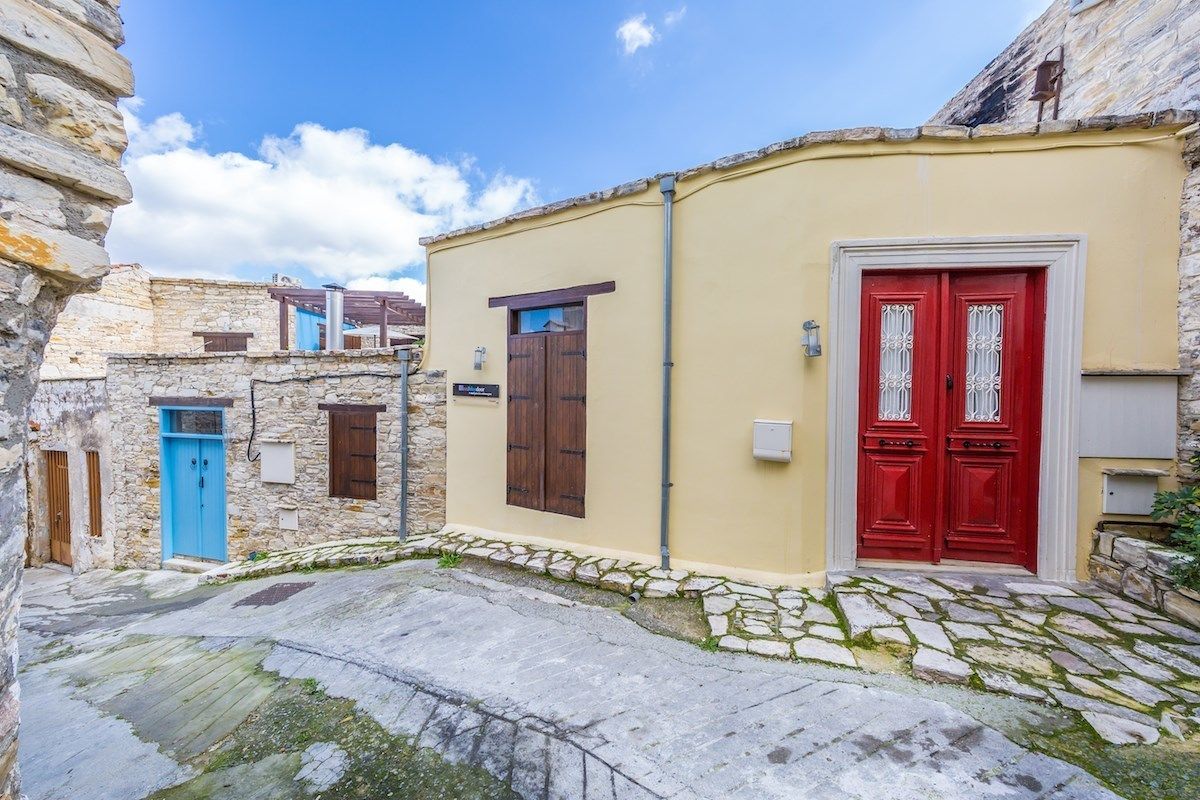 Una calle estrecha con edificios de piedra, una puerta azul y una puerta roja.