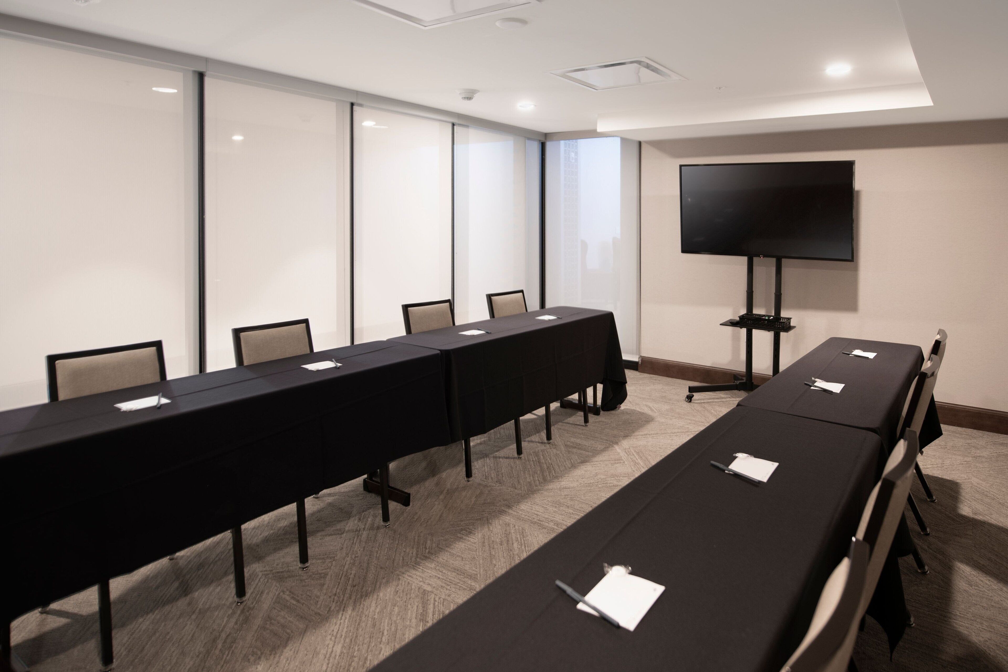 A conference room with a long table, chairs, a flat-screen TV, and a projector.