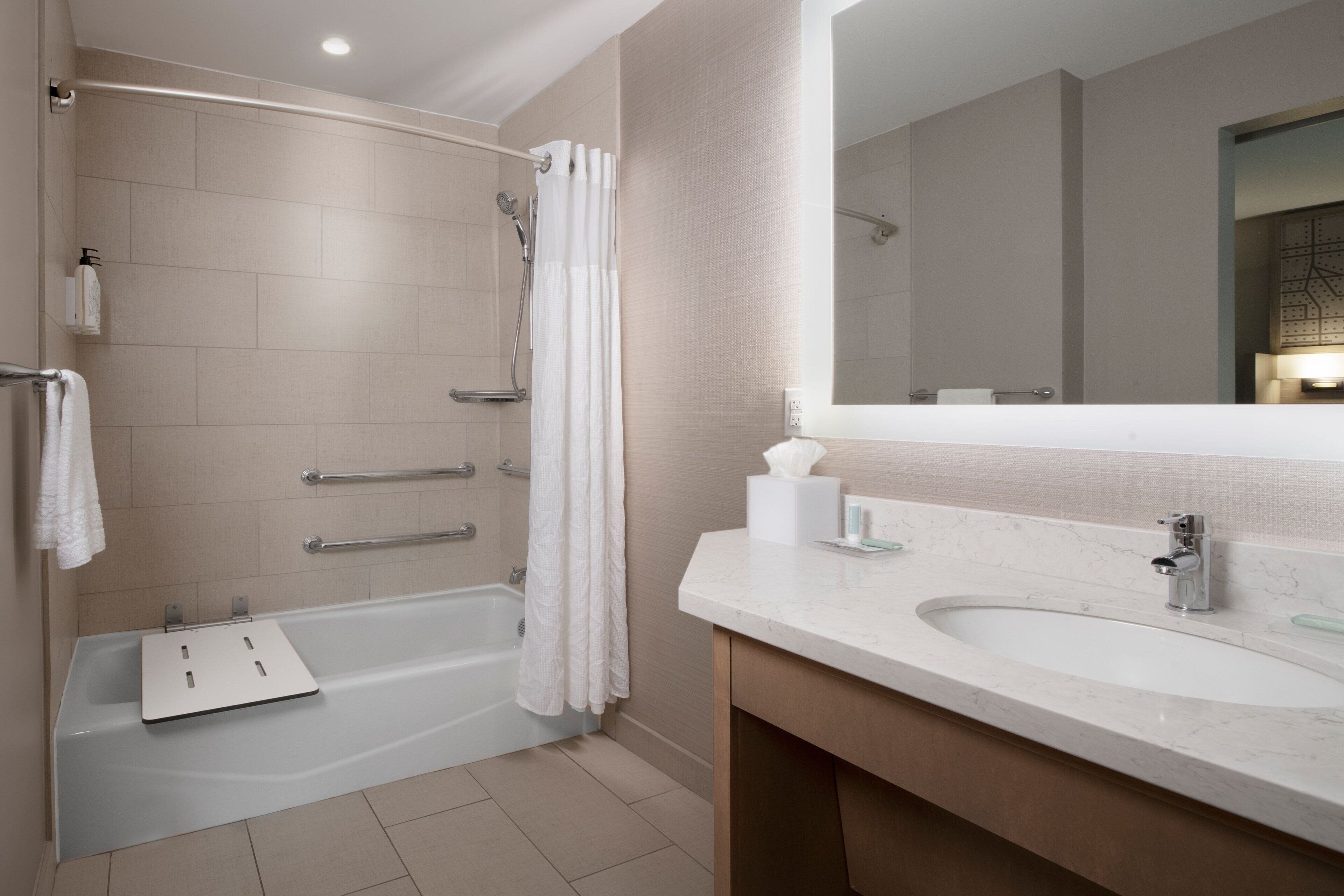 A modern bathroom with a bathtub, shower, and vanity with a sink.
