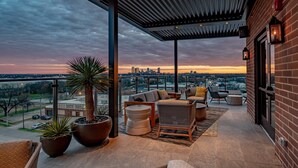 A covered outdoor seating area with a city skyline view, potted plants, and modern furniture. - SpringHill Suites by Marriott Fort Worth Historic Stockyards (Fort Worth)