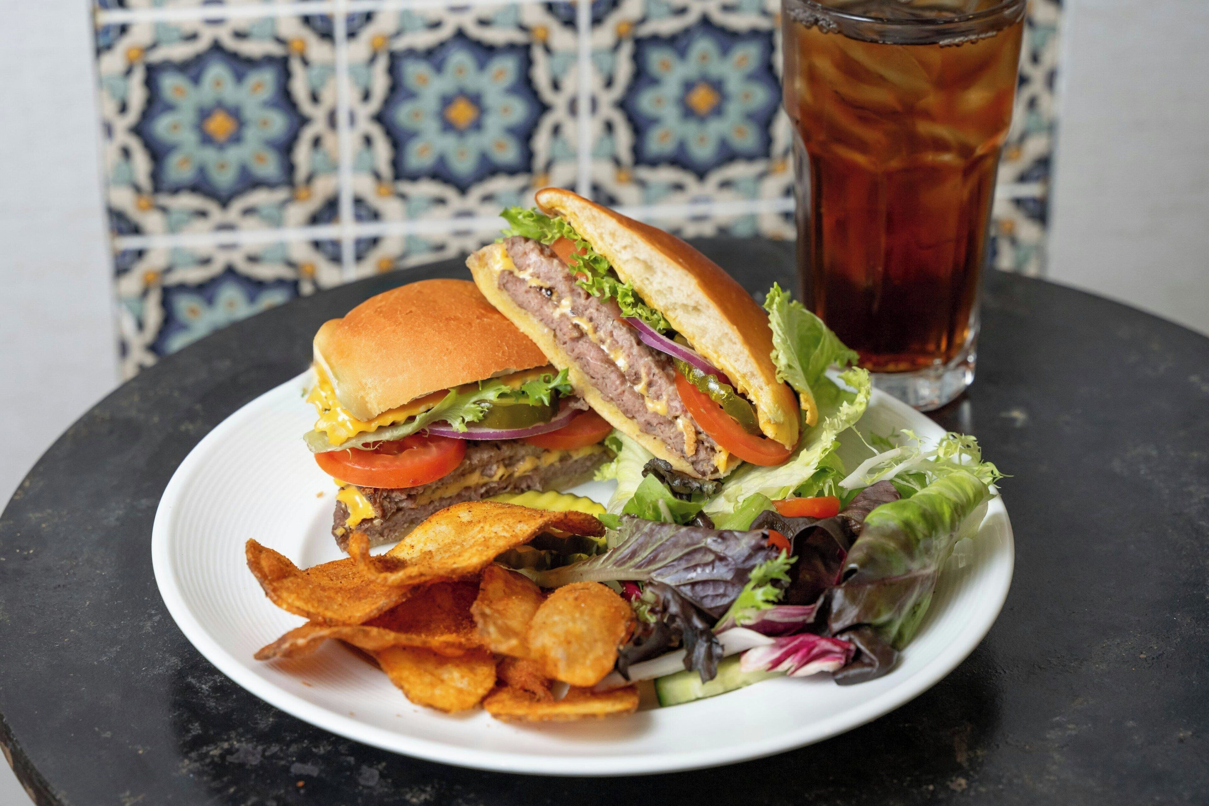 A plate with a sandwich, chips, and a salad, and a glass of iced tea.