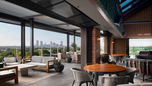A rooftop bar with outdoor seating, a city skyline view, and a brick wall with a sign. - SpringHill Suites by Marriott Fort Worth Historic Stockyards (Fort Worth)