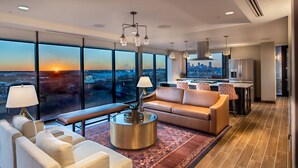 A modern living room with a sofa, armchairs, a coffee table, and a view of the cityscape at sunset. - SpringHill Suites by Marriott Fort Worth Historic Stockyards (Fort Worth)