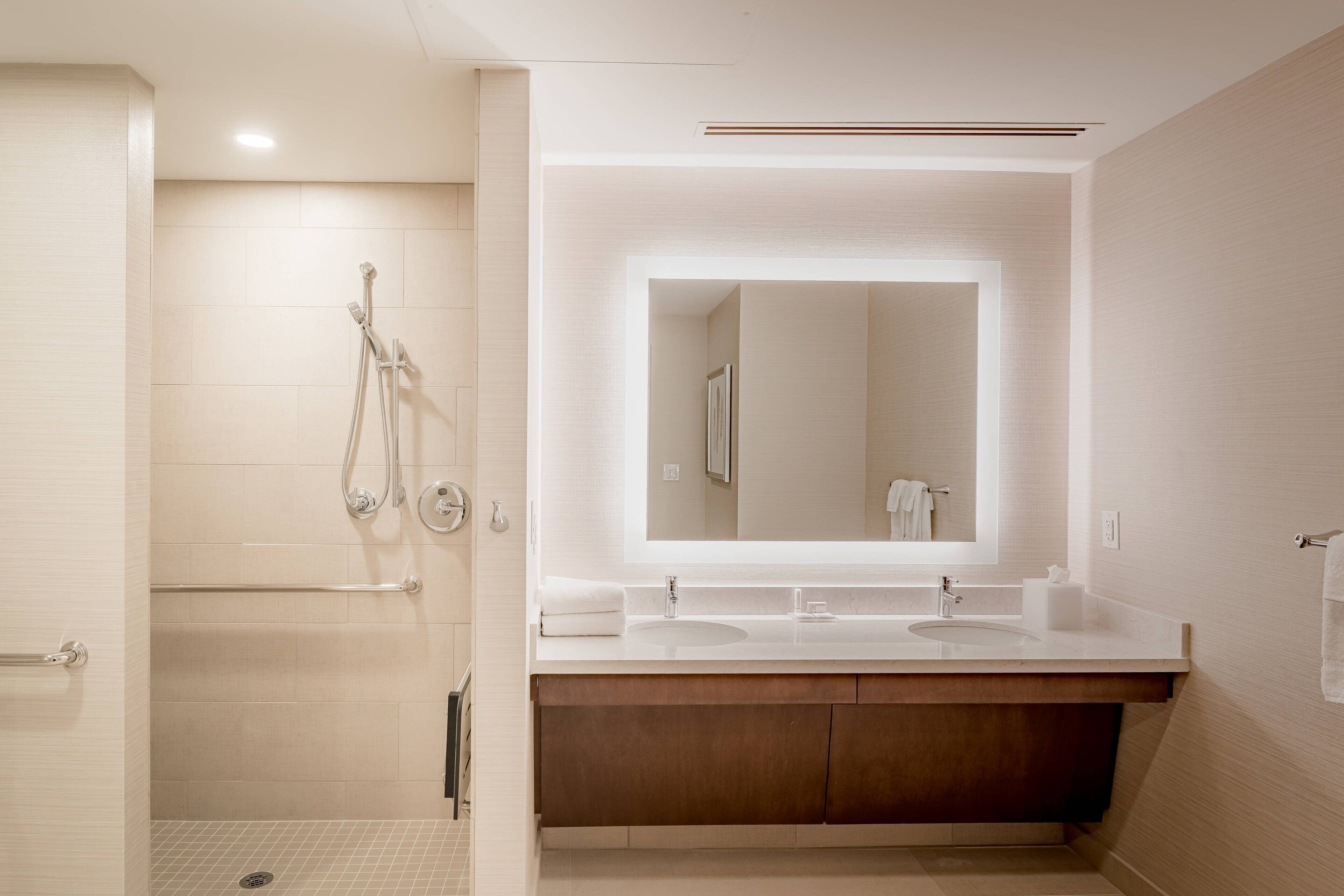 A modern bathroom with a walk-in shower, a large mirror, and a dual sink vanity.