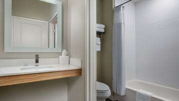 Un baño con lavamanos, espejo, inodoro y bañera.