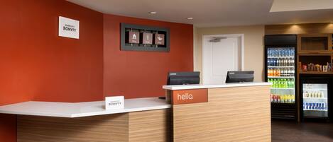 A reception desk with a 'hello' sign, a 'Stay, Work, Play' sign, and a 'Marriott Bonvoy' sign.