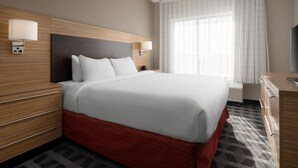 A hotel room with a large bed, wooden headboard, bedside lamps, a desk, and a television.