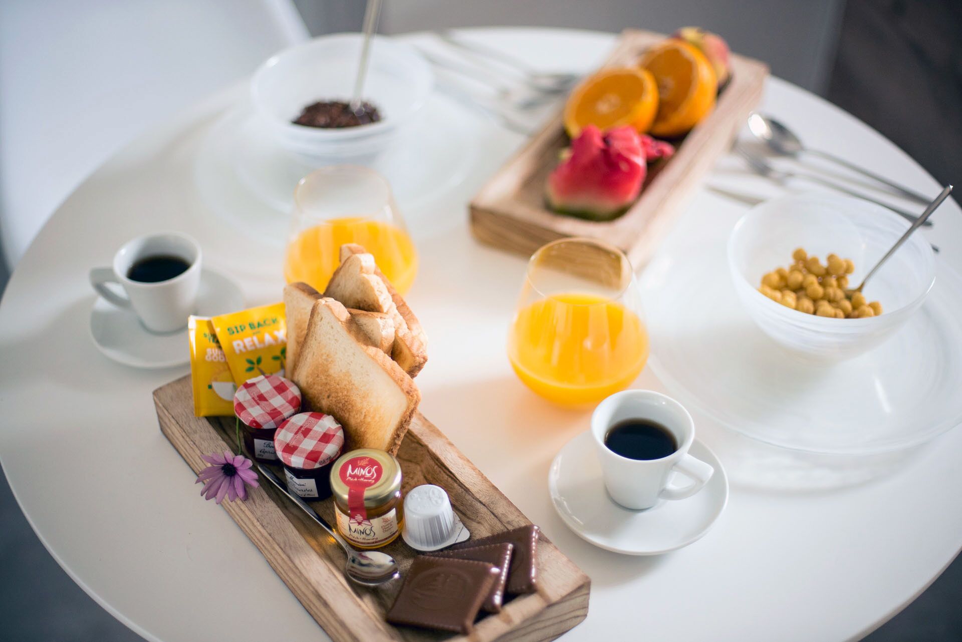 Een ontbijfwagen met toast, jam, honing, een chocoladereep, een fruitschaal en koffiekopjes.