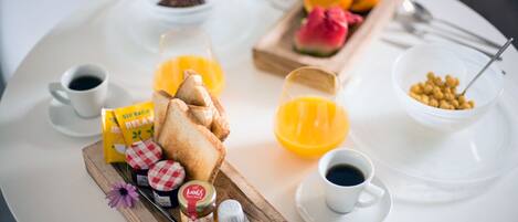 Een ontbijfwagen met toast, jam, honing, een chocoladereep, een fruitschaal en koffiekopjes.