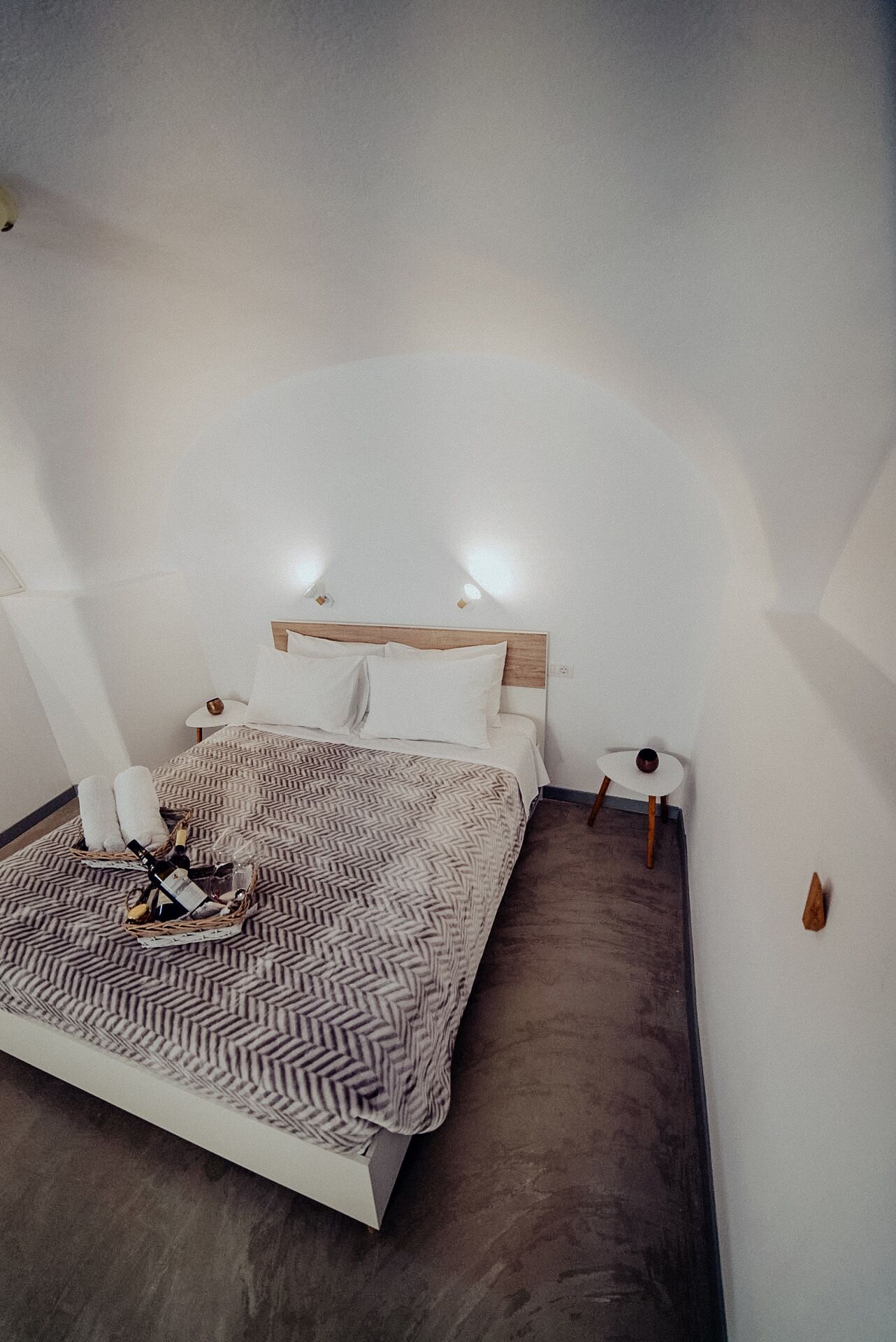 A modern bedroom with a large bed, a bedside table, and a small table with a lamp.