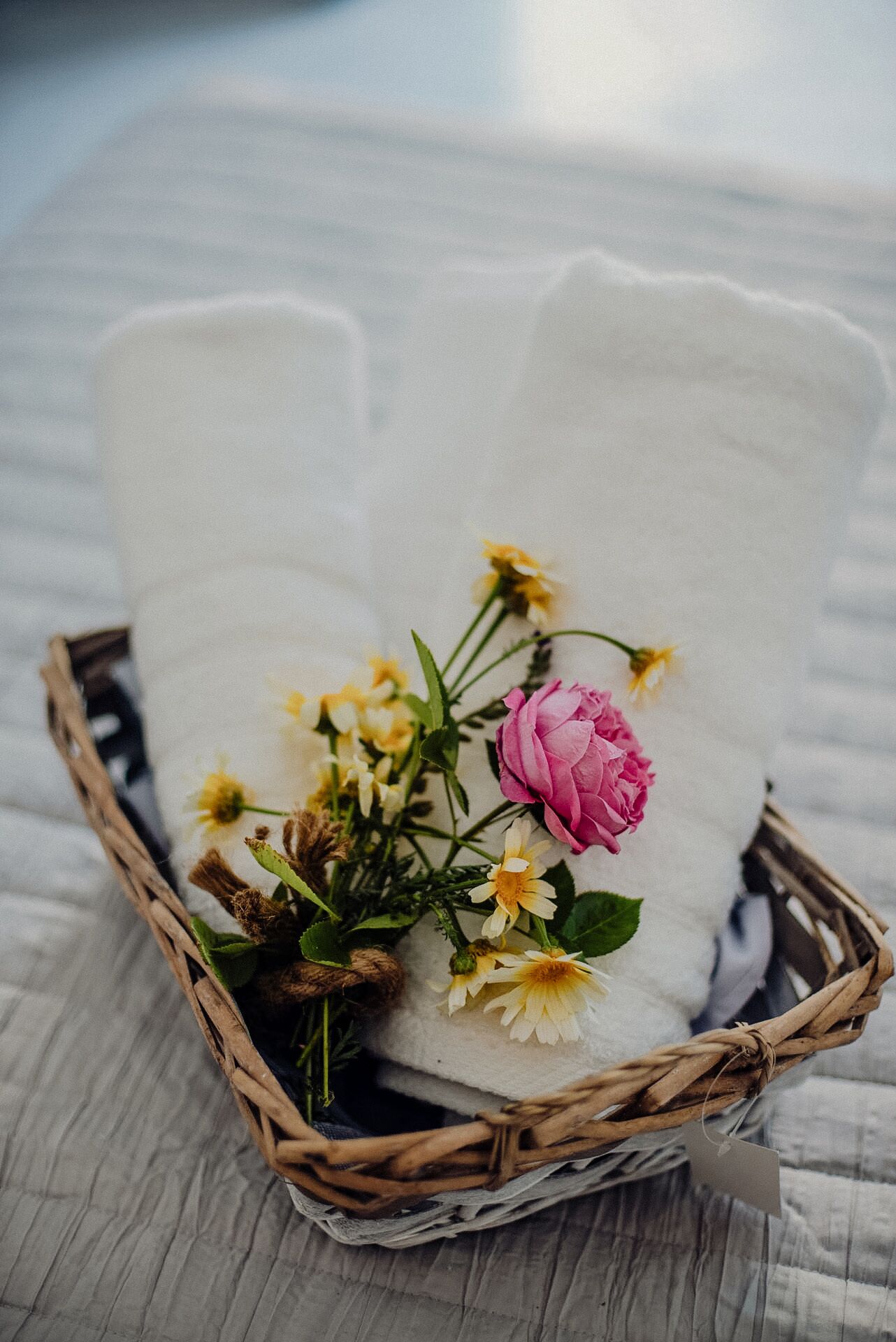 Una cesta de mimbre con un cojín blanco y un ramo de flores.