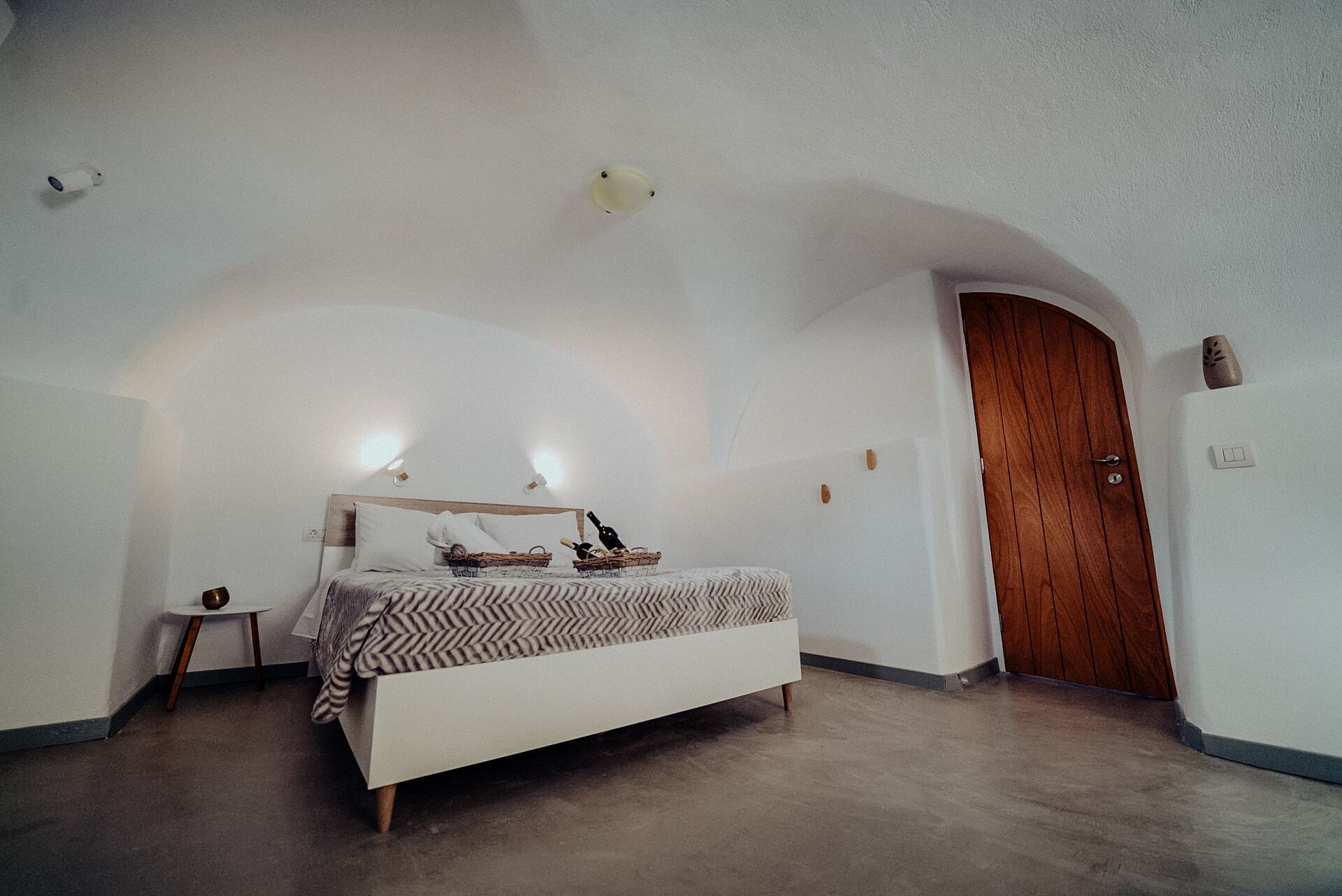 Un dormitorio con cama, mesita de noche, puerta de madera y lámpara.