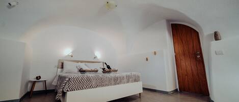 Un dormitorio con cama, mesita de noche, puerta de madera y lámpara.