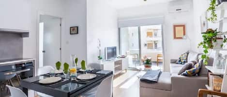 A modern living space with a dining area, kitchen, and a sofa set.