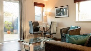 A modern living room with a glass coffee table, a sofa, and a dining area with chairs and a table. - Fabulous Apartment near Edinburgh Center (Edinburgh)