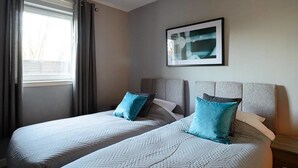 A hotel room with two beds, a window with curtains, and a framed picture on the wall. - Fabulous Apartment near Edinburgh Center (Edinburgh)